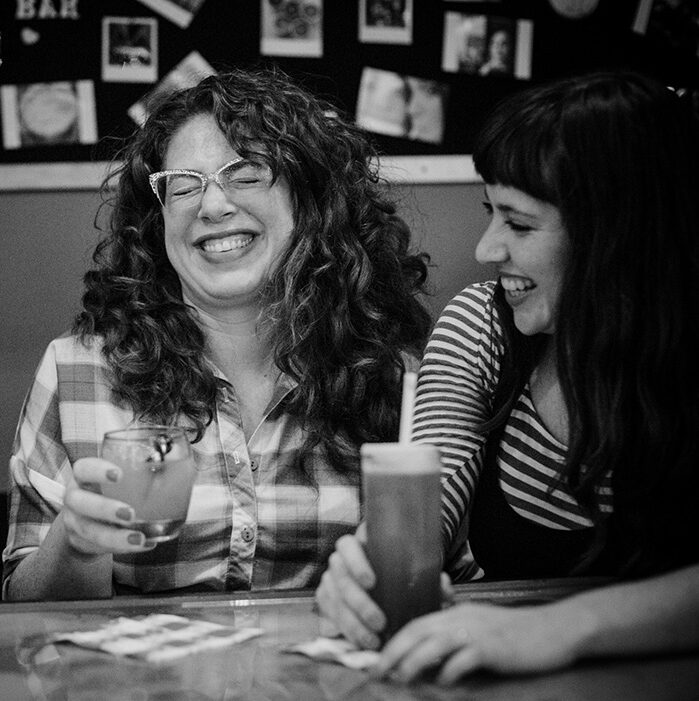 Allison Kave and Keavy Landreth laugh over milkshakes in a diner booth